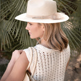 Woman wearing a Ninakuru Panama hat with vegan band and peacock feather.
