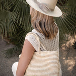 Woman wearing a Ninakuru Panama hat with vegan band and peacock feather.