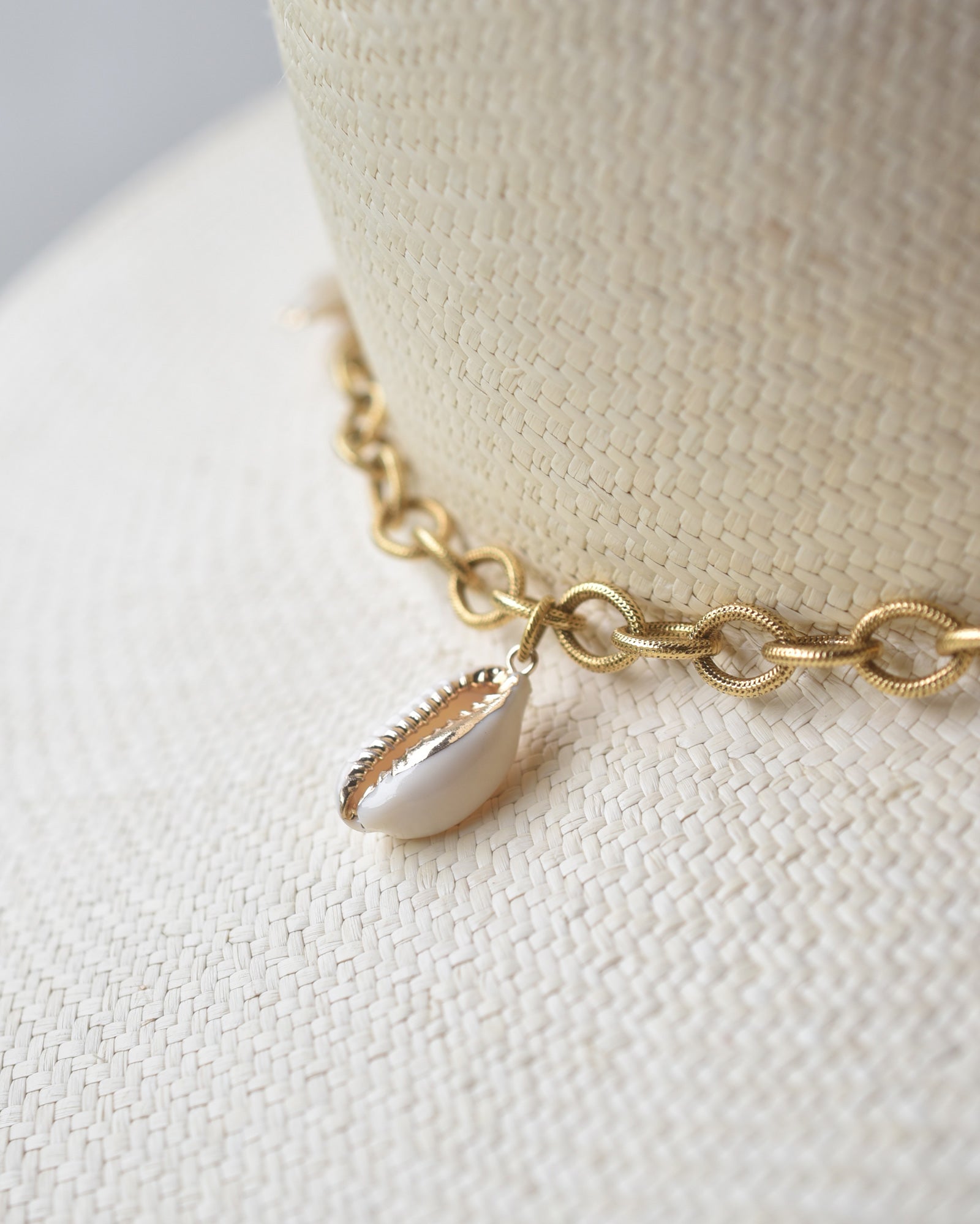 Ninakuru Panama straw hat with gold tone chain and seashells.