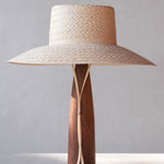 Woven straw hat with wooden base on a gray background