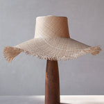 Woven straw hat on a wooden stand against a gray background